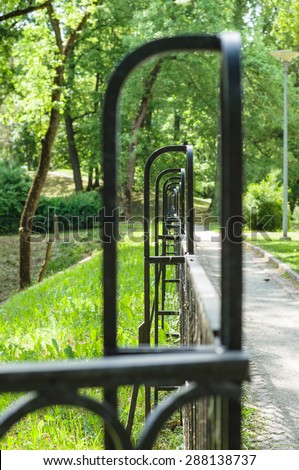 Abstract vanishing decorative wrought iron fence in summer park