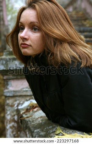 Sad red-haired woman in the autumn park.