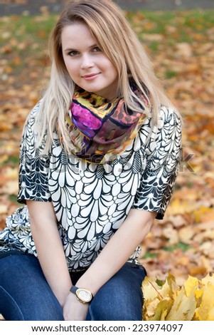 Beautiful blonde smiling, looking at the camera. She walks in autumn park.