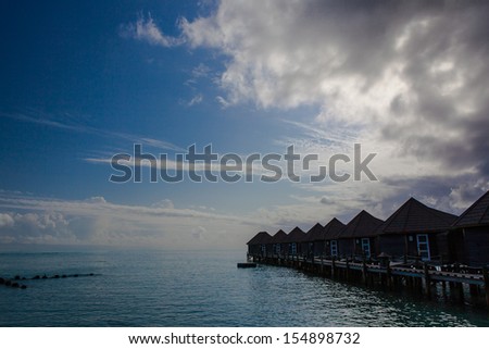 Island in ocean, overwater villa. Maldives.