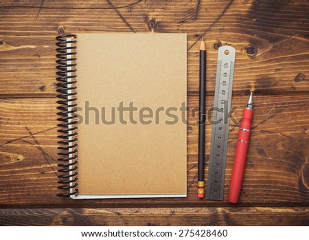 Split toned image of a notepad and office supplies on a vintage wooden desk