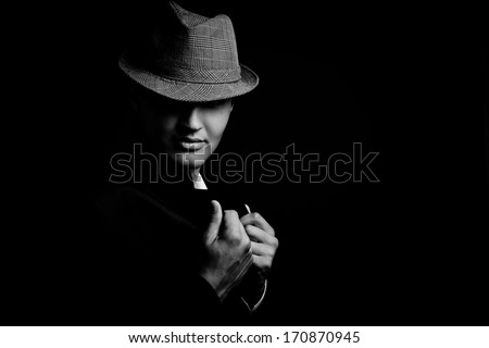 low key portrait of young gangster with hat in the darkness. Black and white image