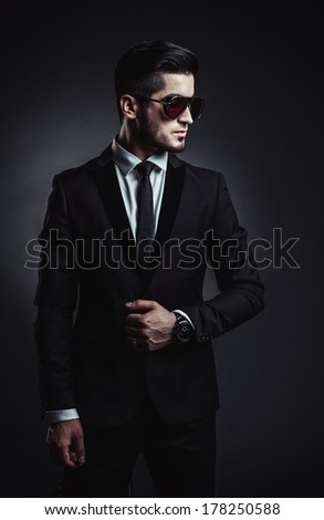 Portrait of handsome stylish man in elegant black suit and sunglasses