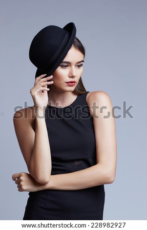 high fashion portrait of elegant woman in black and white hat and dress. Studio shot