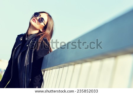 fashion model in sunglasses and black leather jacket posing outdoor