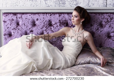 Portrait of beautiful bride lying in the bed. Wedding dress, makeup, hair