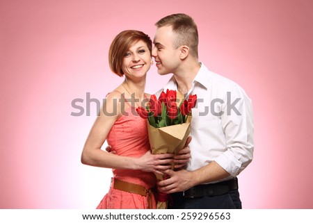 Man surprising his girlfriend with flowers, good emotions , pink background