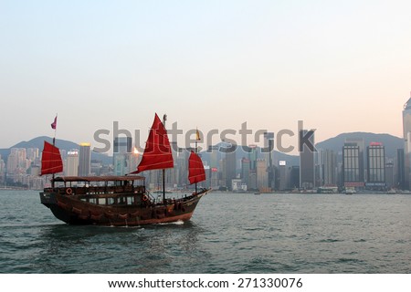 HONG KONG - APR 14, 2014: A traditional Junk boat in Victoria Harbor in Hong Kong, China. Victoria Harbour is a natural landform harbour situated between Hong Kong Island and Kowloon in Hong Kong.