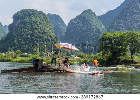 YANGSHUO, CHINA - MAY 01, 2015: Bamboo rafting in the Yulong River surrounded by dramatic landscape of limestone karst. The rafts are built in the traditional design which is still used by fisherman.