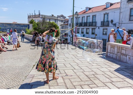 LISBON, PORTUGAL - MAY 27, 2015: A person entertain the crowd gathered at Largo das Portas do Sol in Lisbon Portugal. Outdoor entertainment is the part of European culture.