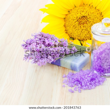 Lavender, bath salt and soap with sunflower on wooden table.