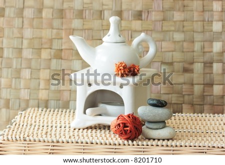 Fragrance lamp for meditation with dry aromatic flowers of orange color and a pile of zen stones