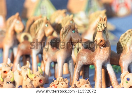Many joyful toy horses and cows made of clay. Shallow depth of field