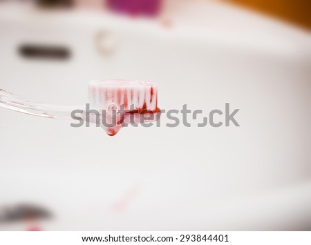 scurvy in a bubble toothpaste on the toothbrush on the white sink. Blood on the toothbrush.
