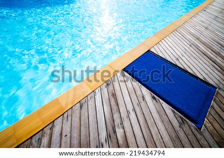 Swimming pool with concrete and wooden deck as a background , blue swimming pool with wood flooring stripes summer vacation