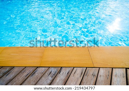 Swimming pool with concrete and wooden deck as a background , blue swimming pool with wood flooring stripes summer vacation