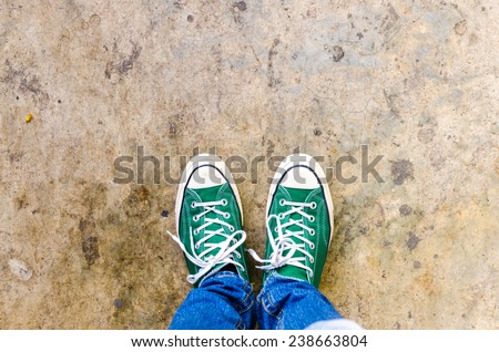 green Sneakers shoes walking on Dirty concrete top view , Canvas shoes walking on concrete