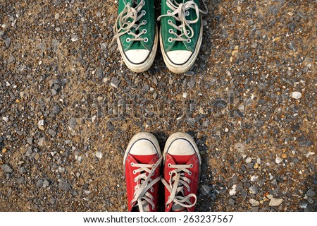Red and green Sneakers shoes walking on gravel road , Canvas shoes walking on gravel road , two sneakers behind each others as a sign of love , Sneakers shoes Couple