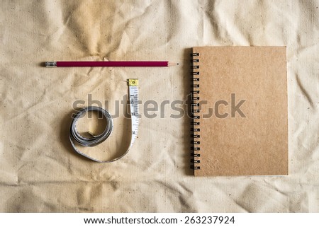 Pencil ,notebook ,tape measure on Brown canvas fabric crease, Measurement Tools on Brown canvas fabric crease