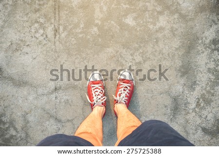Red Sneakers shoes walking on Dirty concrete top view with sunlight , Canvas shoes walking on Dirty concrete