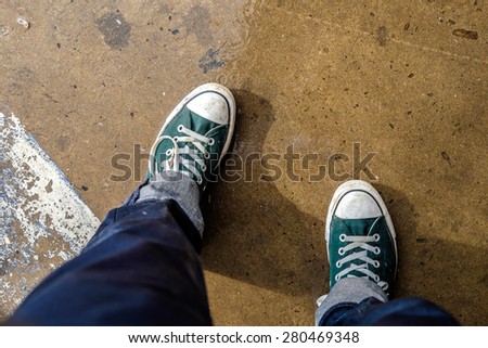 Green Sneaker walking on wet ground ,top view ,hipster