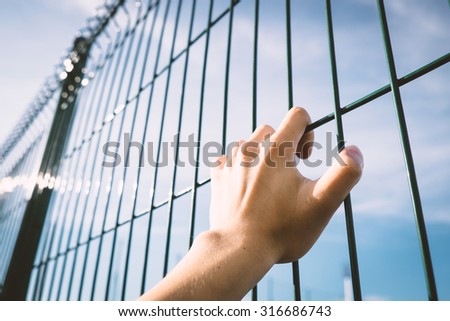 Man hand on steel cage with sky.concept of freedom