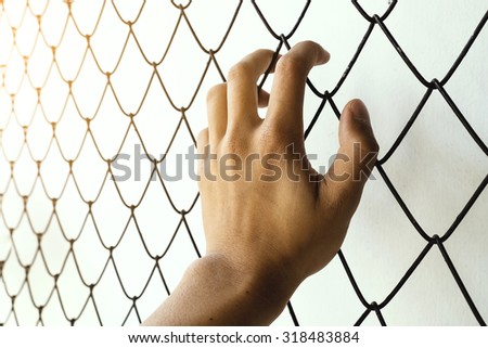 Hand on steel cage with Dark look, concept of the freedom
