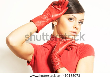 Attractive brunet in red blouse and red gloves near face