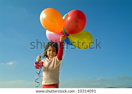 girl holding balloons against blue sky