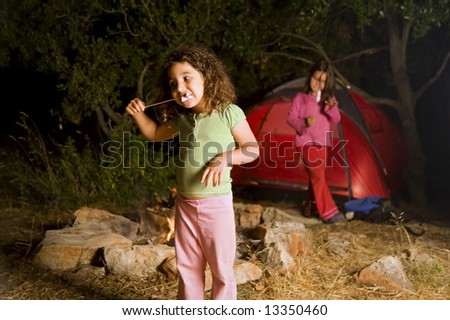 two girls at a camp eating marshmallow
