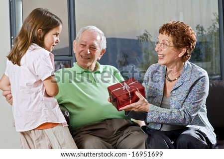 grandparents giving gift to grandchild at home