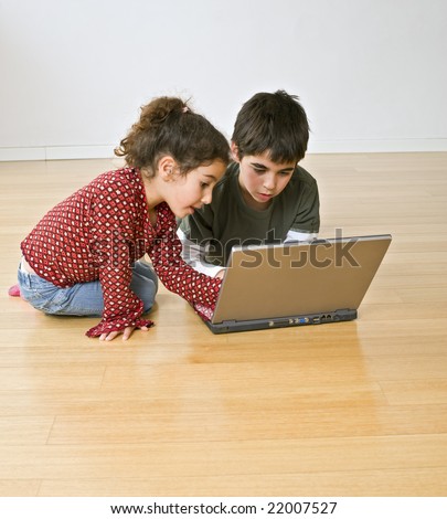 two kids with laptop computer on the floor