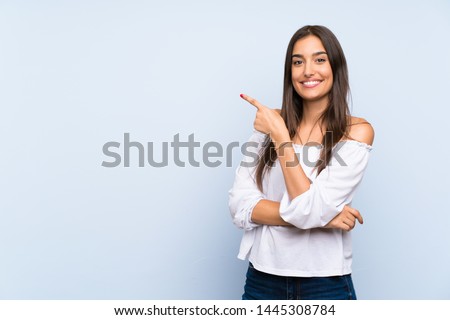Young woman over isolated blue background pointing finger to the side ストックフォト © 