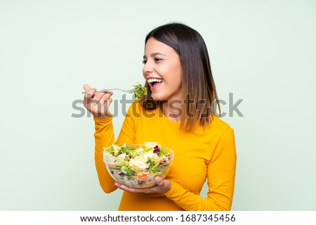 Young woman with salad over isolated green wall Foto stock © 