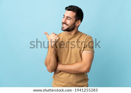 Young handsome man with beard over isolated background pointing to the side to present a product ストックフォト © 