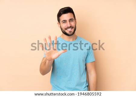 Caucasian handsome man isolated on beige background counting five with fingers 商業照片 © 