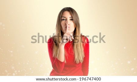 girl doing silence gesture over ocher background