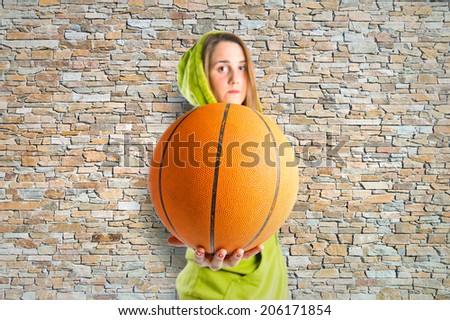 Blonde girl playing basketball over texture background