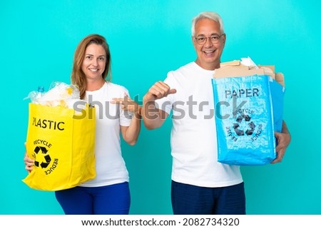 Middle age couple holding a recycling bags full of paper and plastic isolated on white background proud and self-satisfied in love yourself concept Сток-фото © 