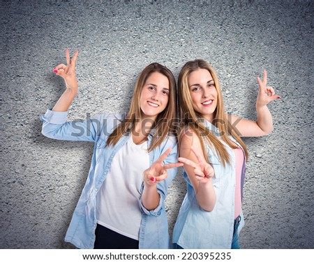 Girls doing victory gesture over textured background