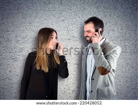 Couple talking to mobile over textured background