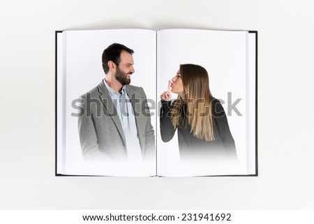 Young girl making silence gesture at her boyfriend  printed on book