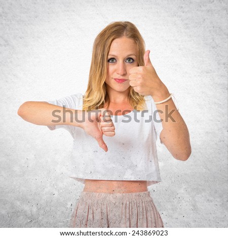Woman making a good-bad sign over textured background