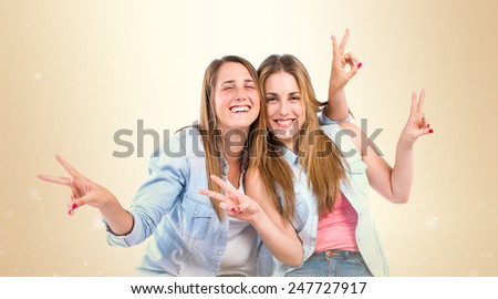 Sisters doing victory gesture over ocher background