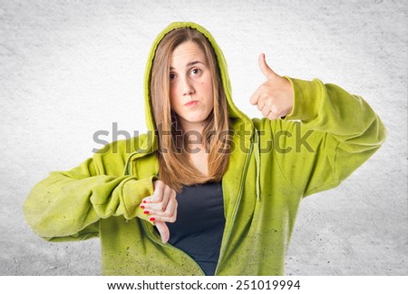 Young redhead making a good-bad sign over textured background