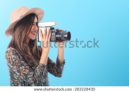 Woman with vintage video camera over colorful background