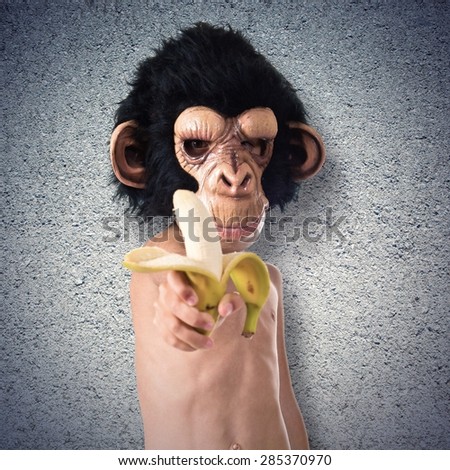 Child with monkey mask holding a banana over textured background