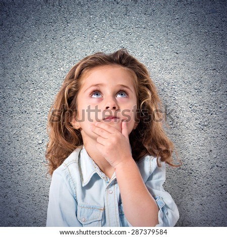 Blonde little girl thinking over textured background