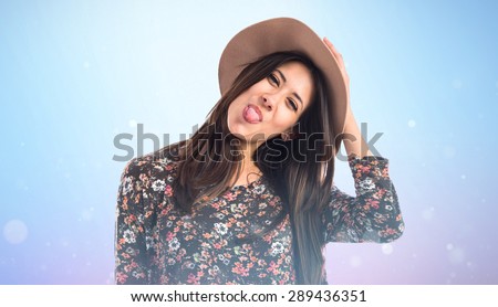 Woman taking out her tongue over blue background