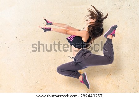 Teenager girl jumping in hip hop style over textured background